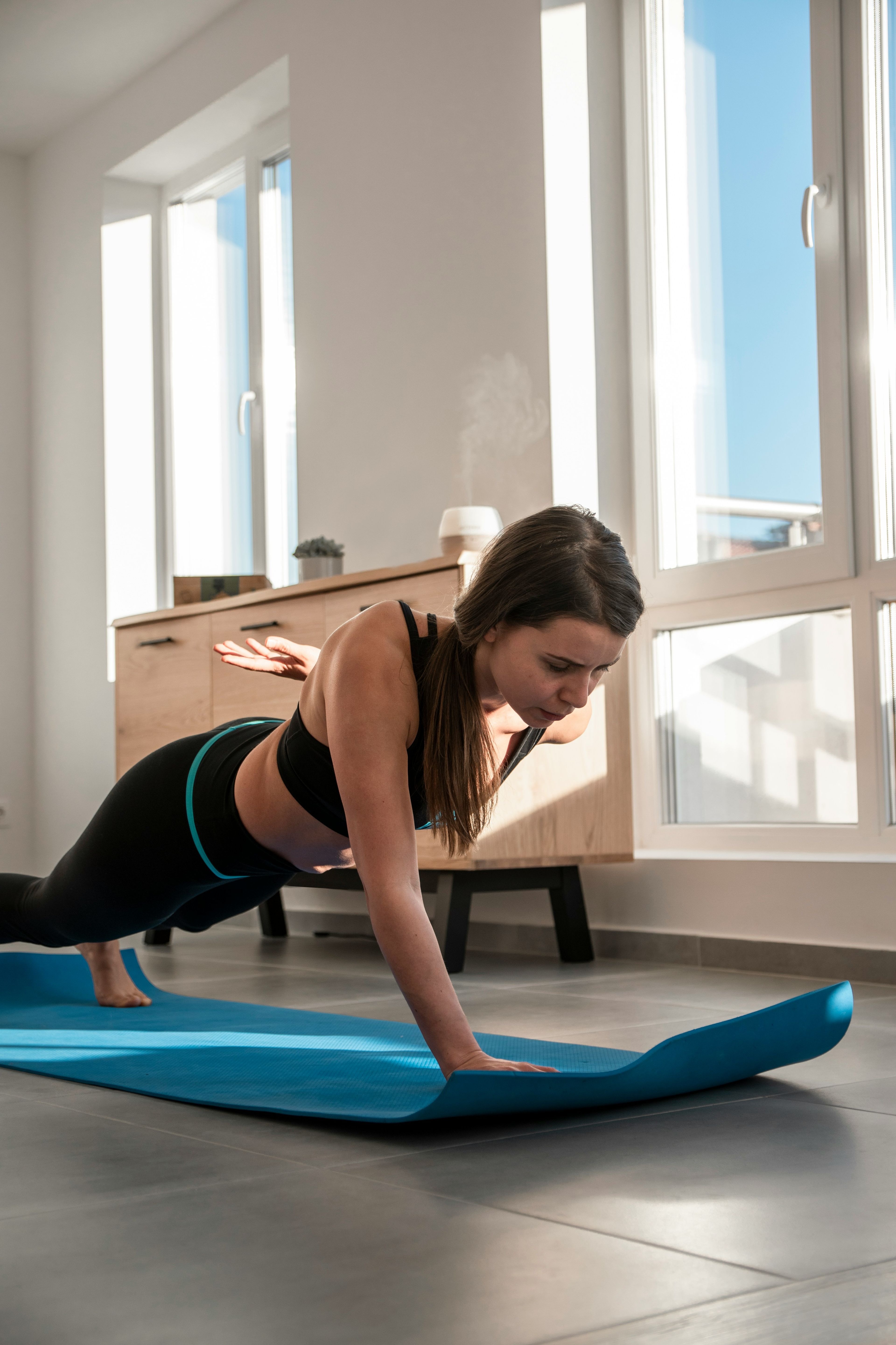 Femme en position de planche sur un tapis de sol bleu
